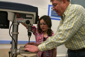 young girl learning to use power tools